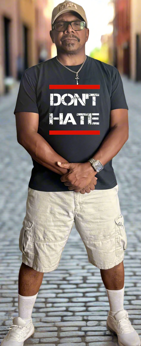 Man wearing a black t-shirt with 'DON'T HATE' text on a city street.